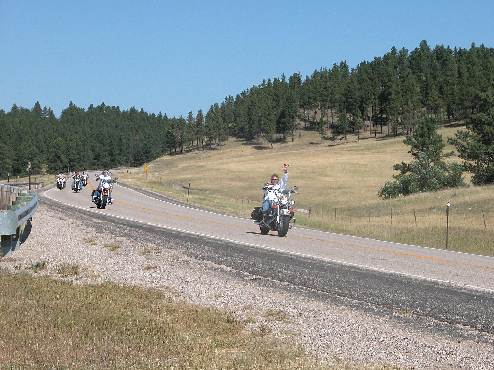 Two motorcyclists riding along an open country road.