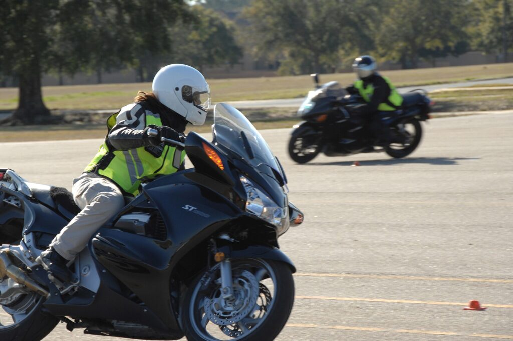 Motorcyclists riding in formation through a marked course during a rider certification class.